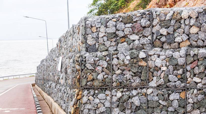Three layers of galfan double twisted woven gabions are installed at the bottom of steep hill.